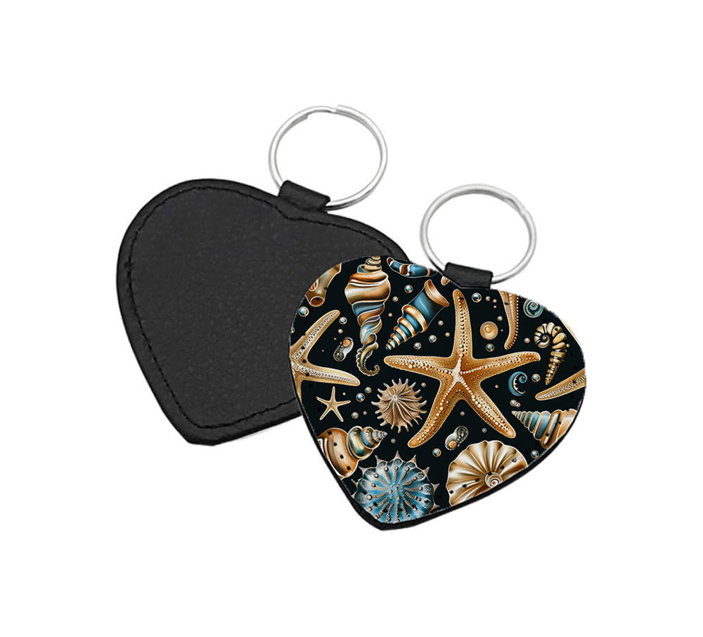 Portachiavi a forma di Cuore CP-0028 in pelle PU con grafica marina a stelle marine e conchiglie dorate e blu ottanio su sfondo nero, retro nero in pelle e anello in acciaio