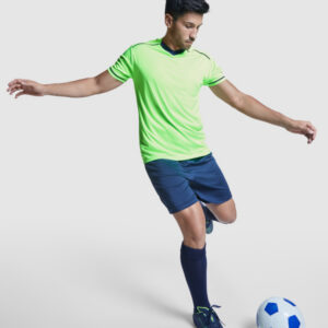 Modello con divisa da calcio e kit allenamento traspirante verde lime con pantaloncini e calzettoni blu