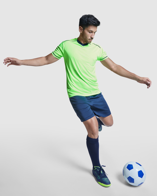 Modello con divisa da calcio e kit allenamento traspirante verde lime con pantaloncini e calzettoni blu